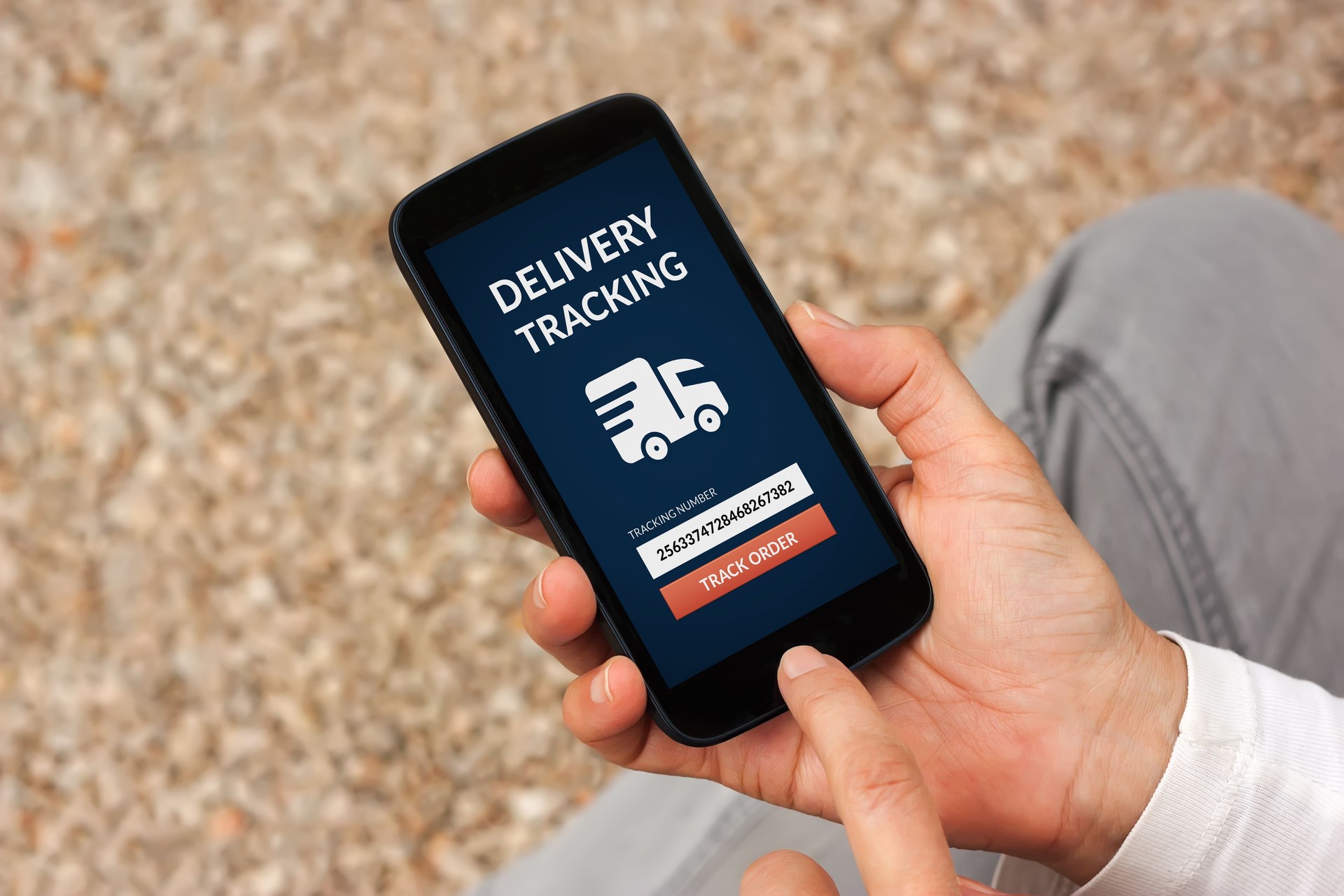 Hands holding smart phone with delivery tracking concept on screen